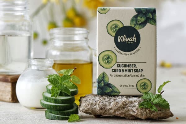 Caja con estampado verde, pepinos cortados en primer plano y contenedores al fondo
